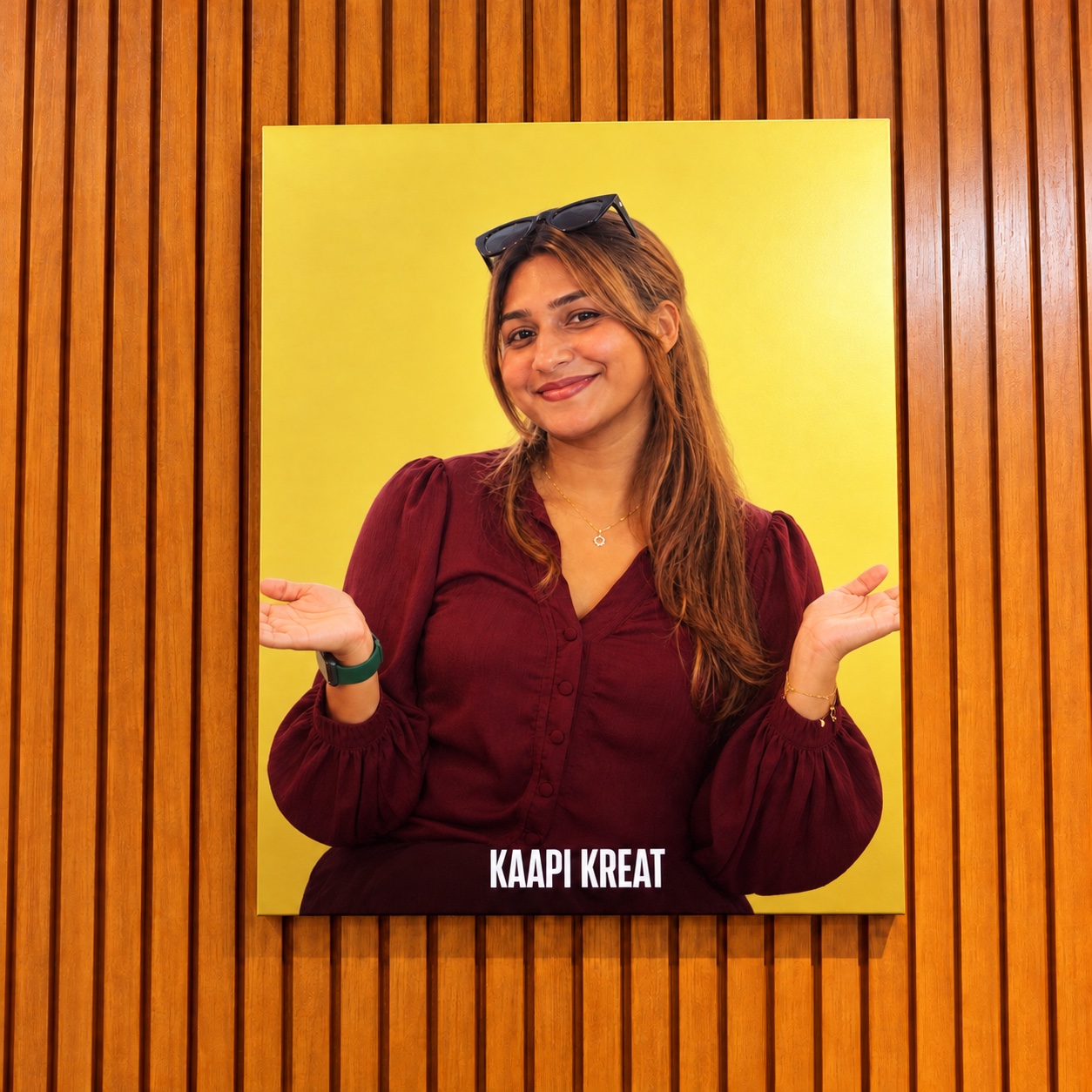 Resshma Mohan smiling in a portrait mounted on a wooden wall, with KAAPI KREAT lettering below